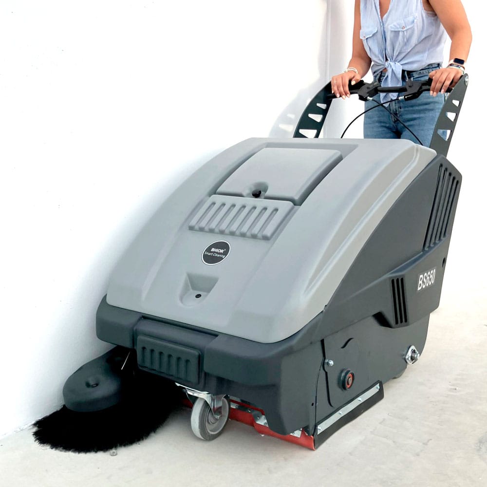 Operario de barredora industrial bs680 manual limpiando nave industrial.