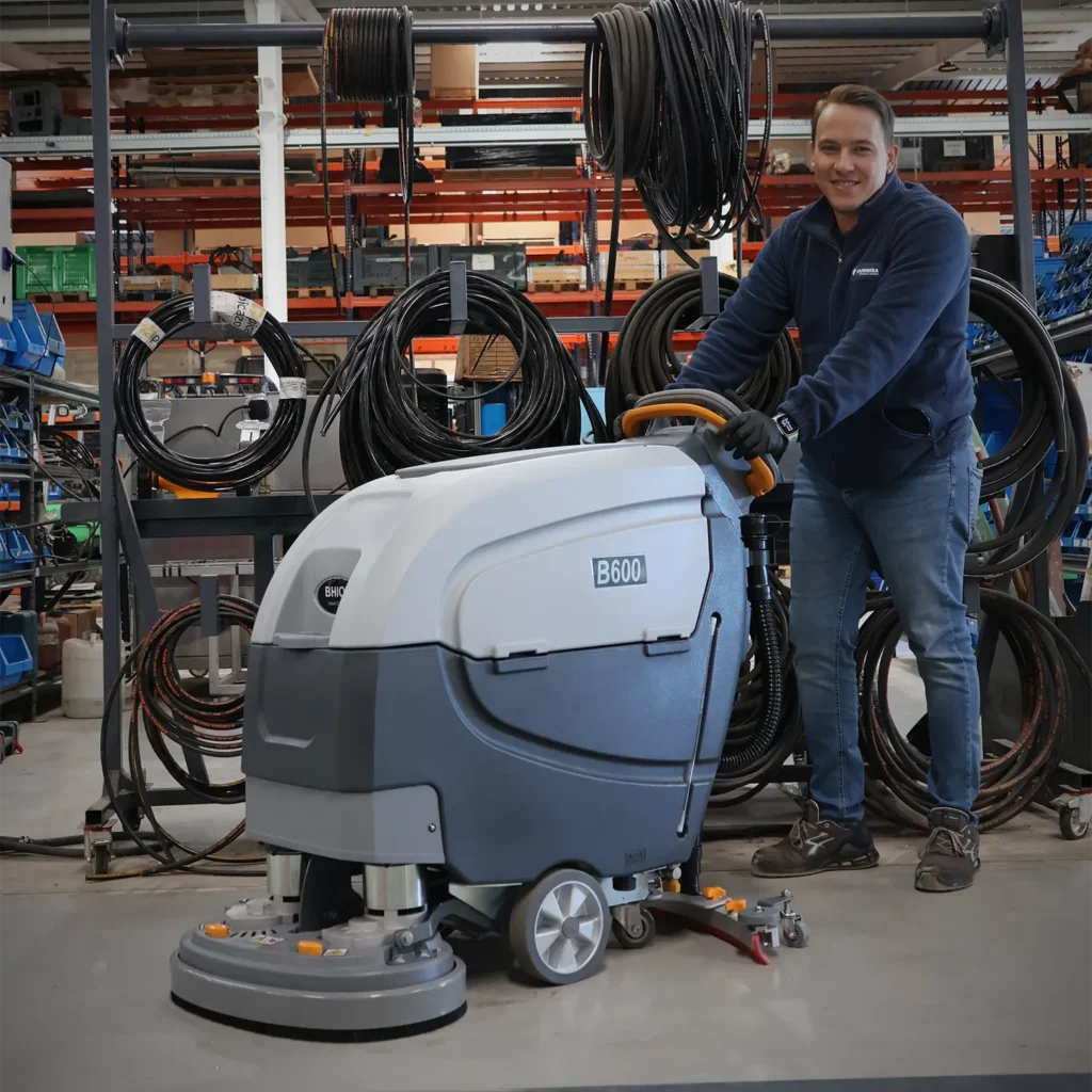 Fregadora B600 limpiando taller mecánico con conductor acompañante.